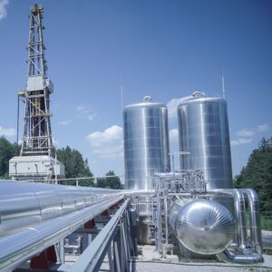 Surface facilities at Eavor’s Geretsried closed-loop geothermal project in Bavaria, Germany, including the Organic Rankine Cycle (ORC) power plant equipment, working-fluid storage tanks, and associated piping infrastructure adjacent to one of the site’s drilling rigs. The installation anchors the world’s first commercial deployment of Eavor’s multilateral Eavor-Loop well system, which generates electricity and district heat without fluid exchange with subsurface formations. Courtesy: Luckypage / Ekkehard Winkler.